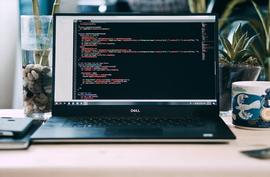 programmer writing code on laptop