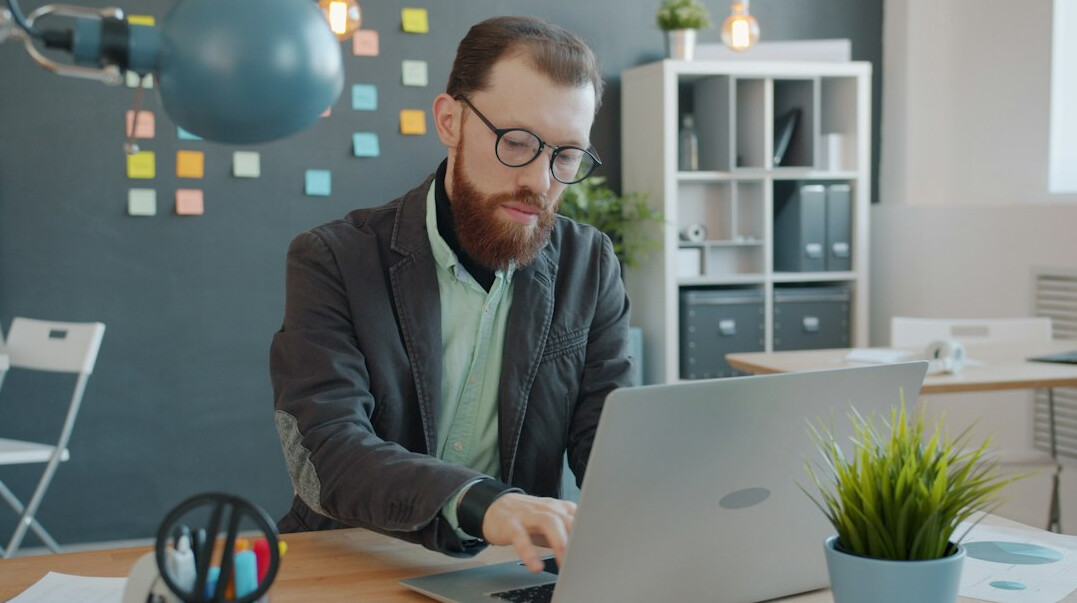 Small team of professionals collaborating around a laptop in an office